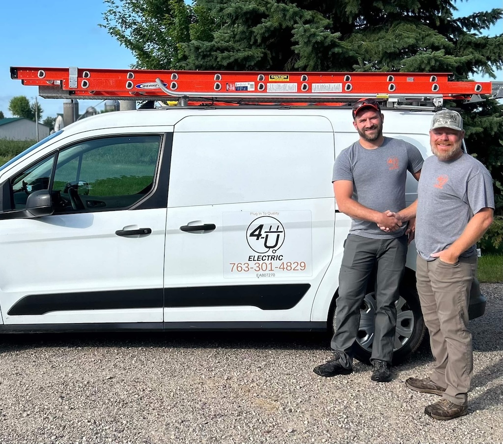 Tom and Mike, friendly electricians from 4-U Electric, shaking hands in front of their work van in Minneapolis
